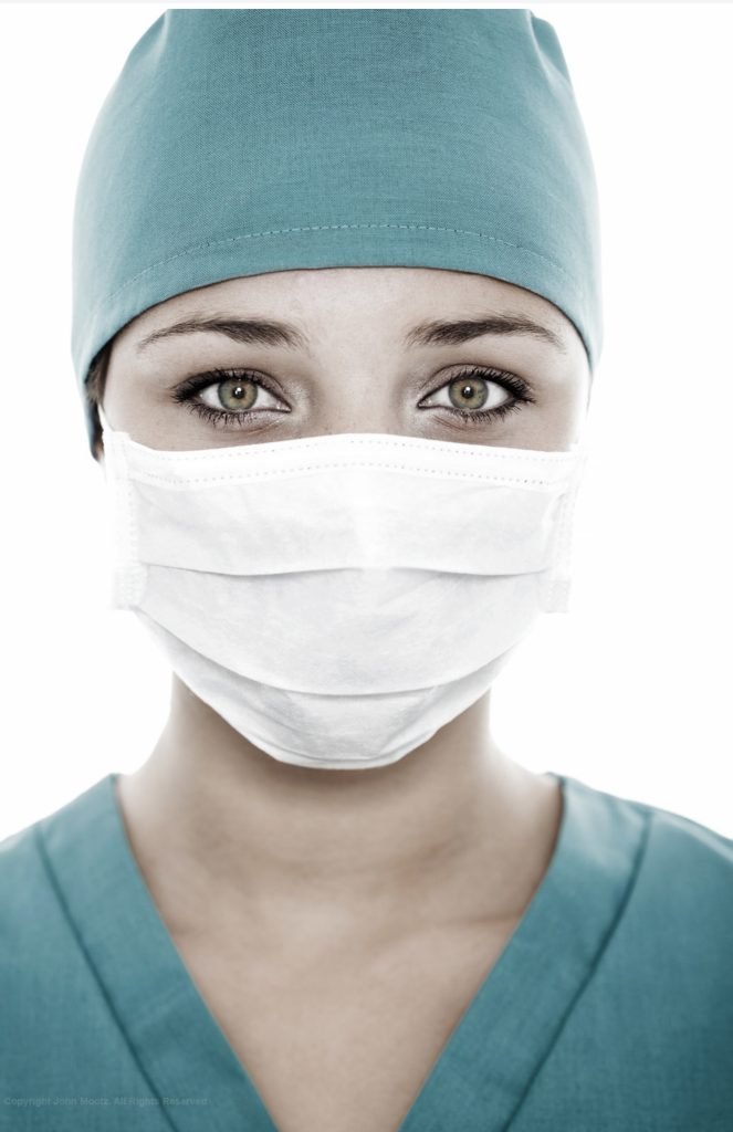 Female healthcare worker in surgical mask and scrubs during a commercial photo shoot in Seattle, captured to honor frontline medical professionals. Makeup by Indigenous Seattle makeup artist Isaac Meyers.