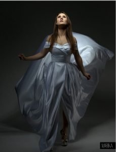 Model in flowing blue gown with long, voluminous hair styled in soft waves, hair by Seattle makeup artist Isaac Meyers