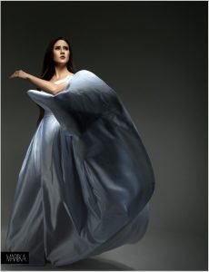 Model in flowing blue gown with long, voluminous hair styled in soft waves, hair by Seattle makeup artist Isaac Meyers